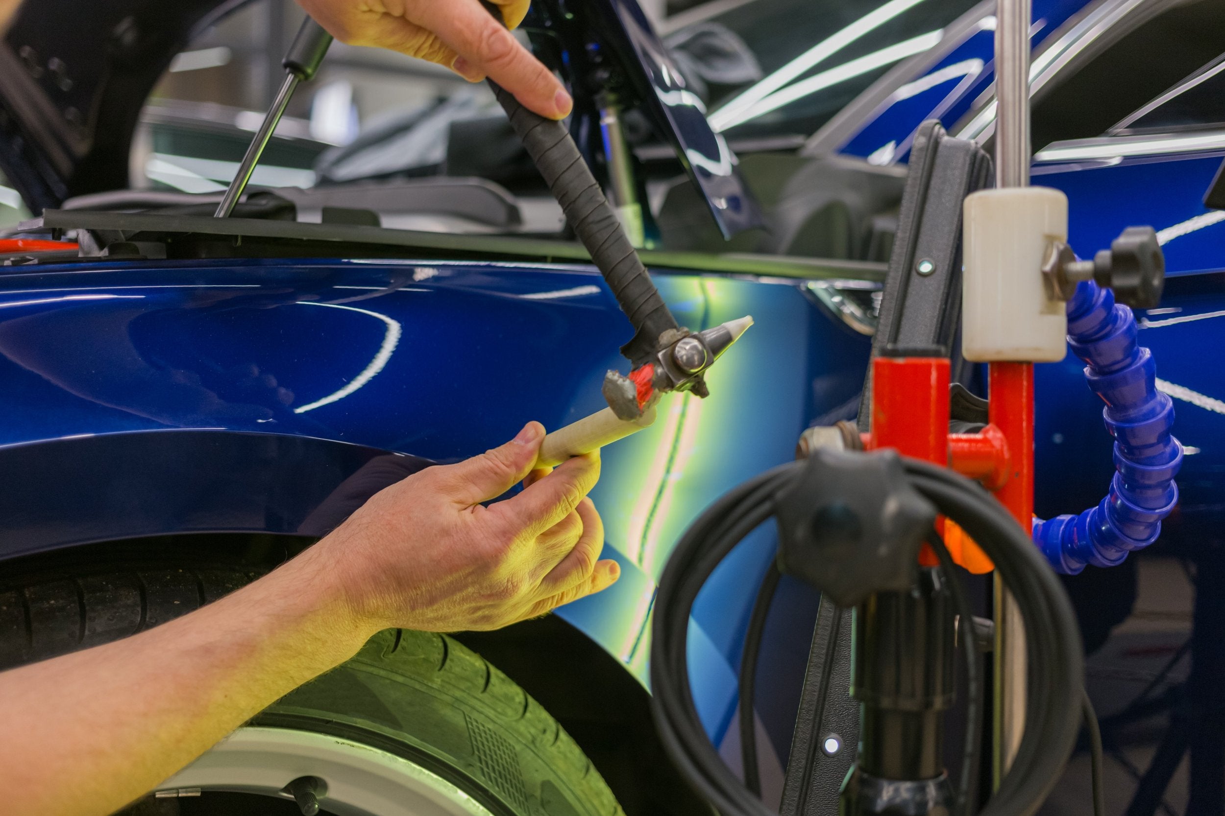 Paintless dent repair technician fixing hail dent on car fender at Apex Precision Repair in Denver